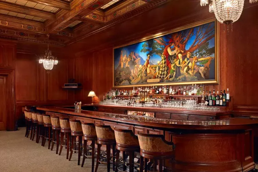 的 bar at the Palace Hotel, which features wood-paneled walls 和 a painting titled 的 Pied Piper of Hamelin.