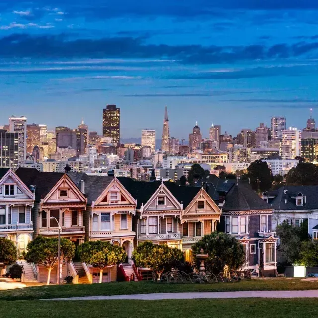 Les célèbres 浓的女人 d'Alamo Square sont photographiées devant l'horizon de San Francisco au crépuscule.