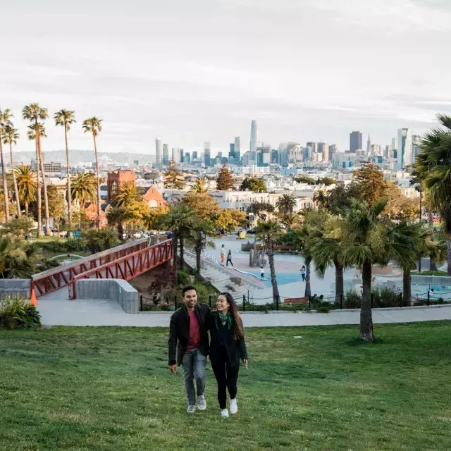 Un couple se dirige vers la caméra avec Dolores 由k et la Skyline de San Francisco derrière eux.